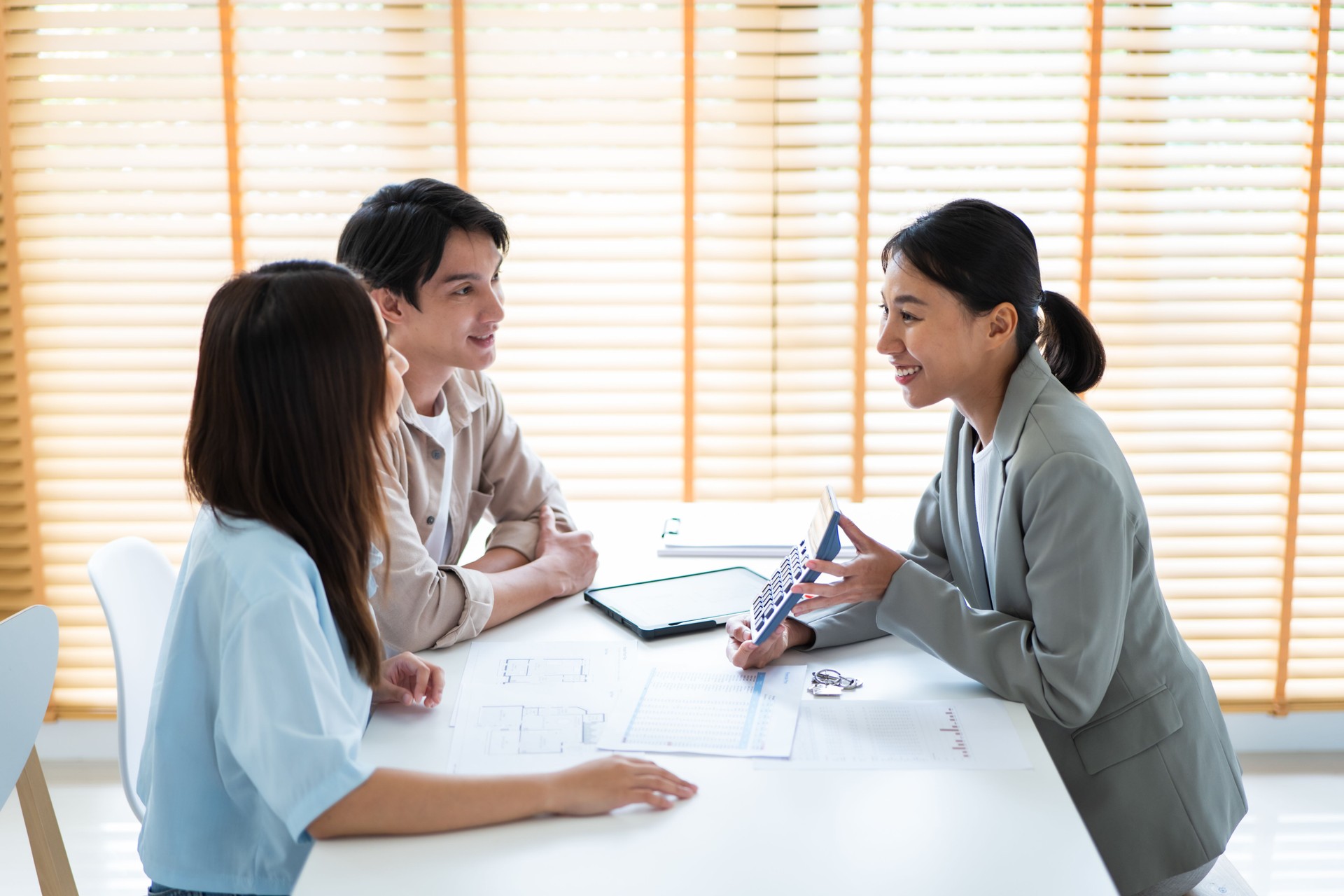 Asian Woman Real Estate Agent Explaining About House Plan to a Young Couple Customer.